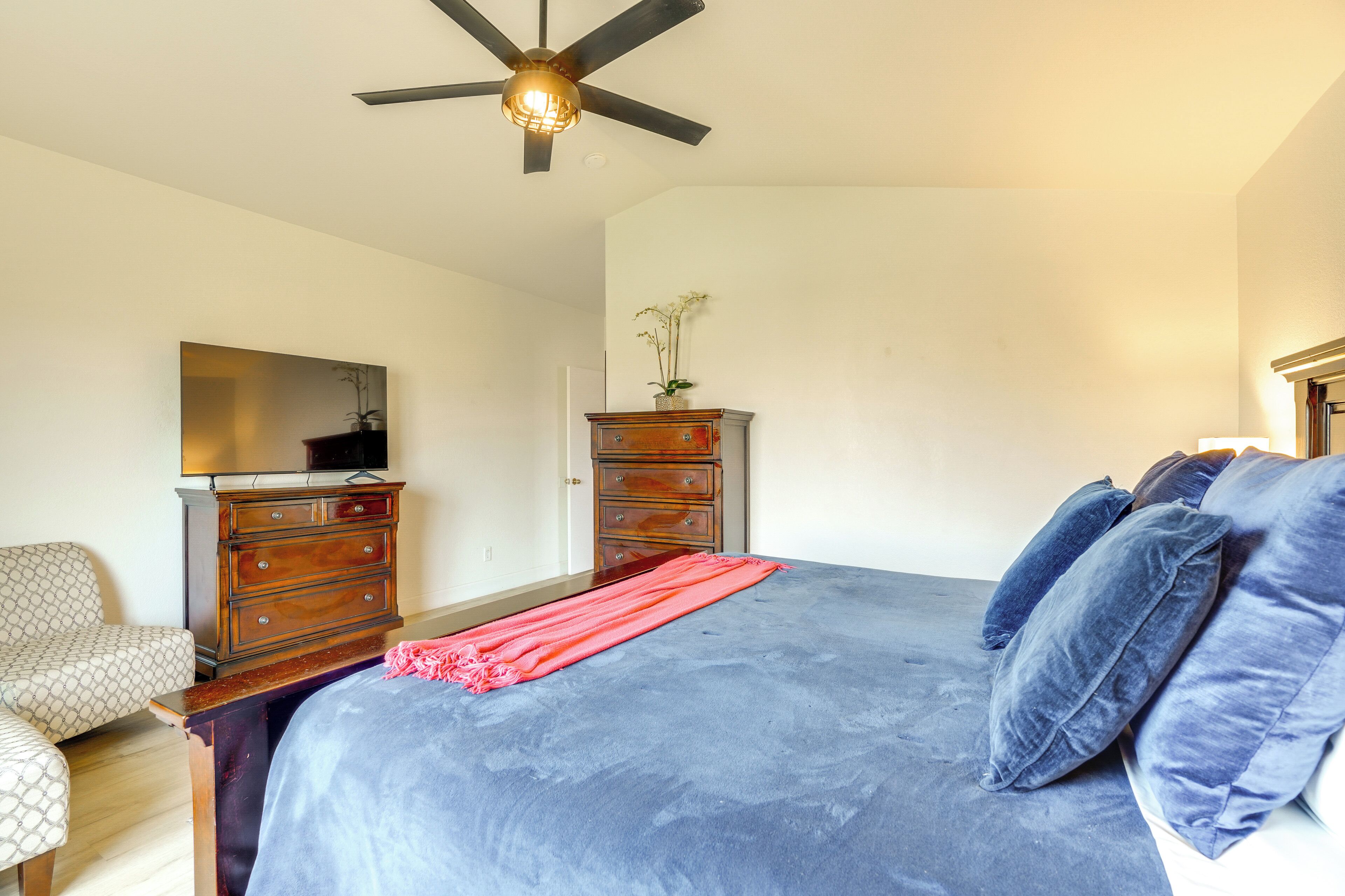 Une chambre à coucher avec un lit, une commode, une chaise et un ventilateur de plafond.