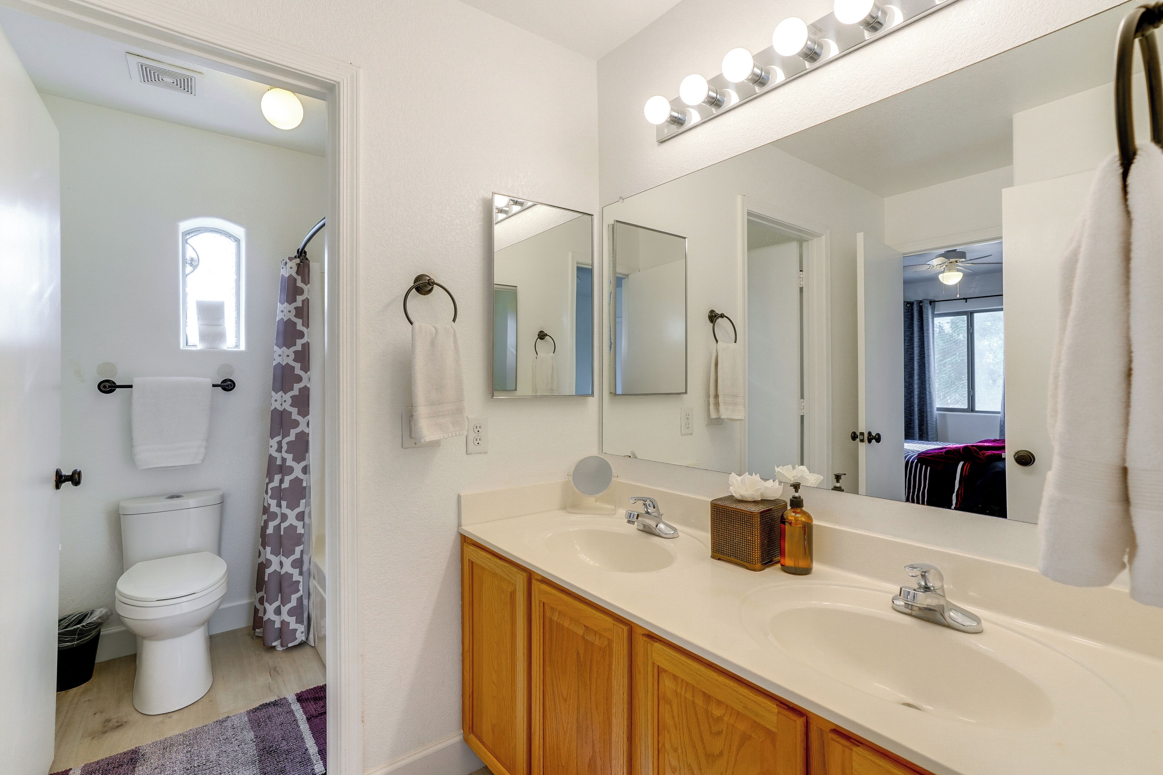 A bathroom with a white sink, vanity, and a large mirror.