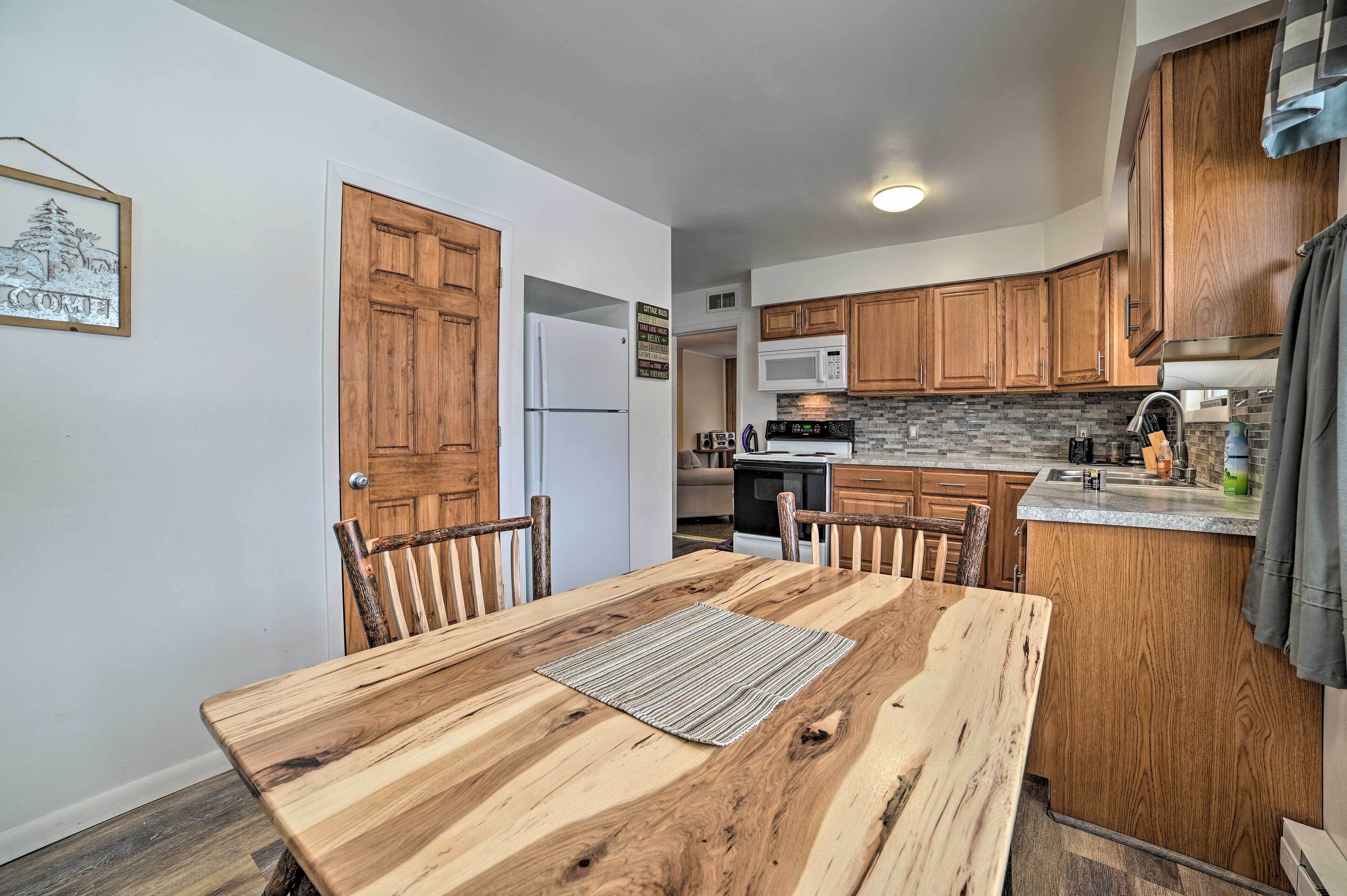 A kitchen with wooden cabinets, a microwave, and a dining area with a wooden table and chairs.