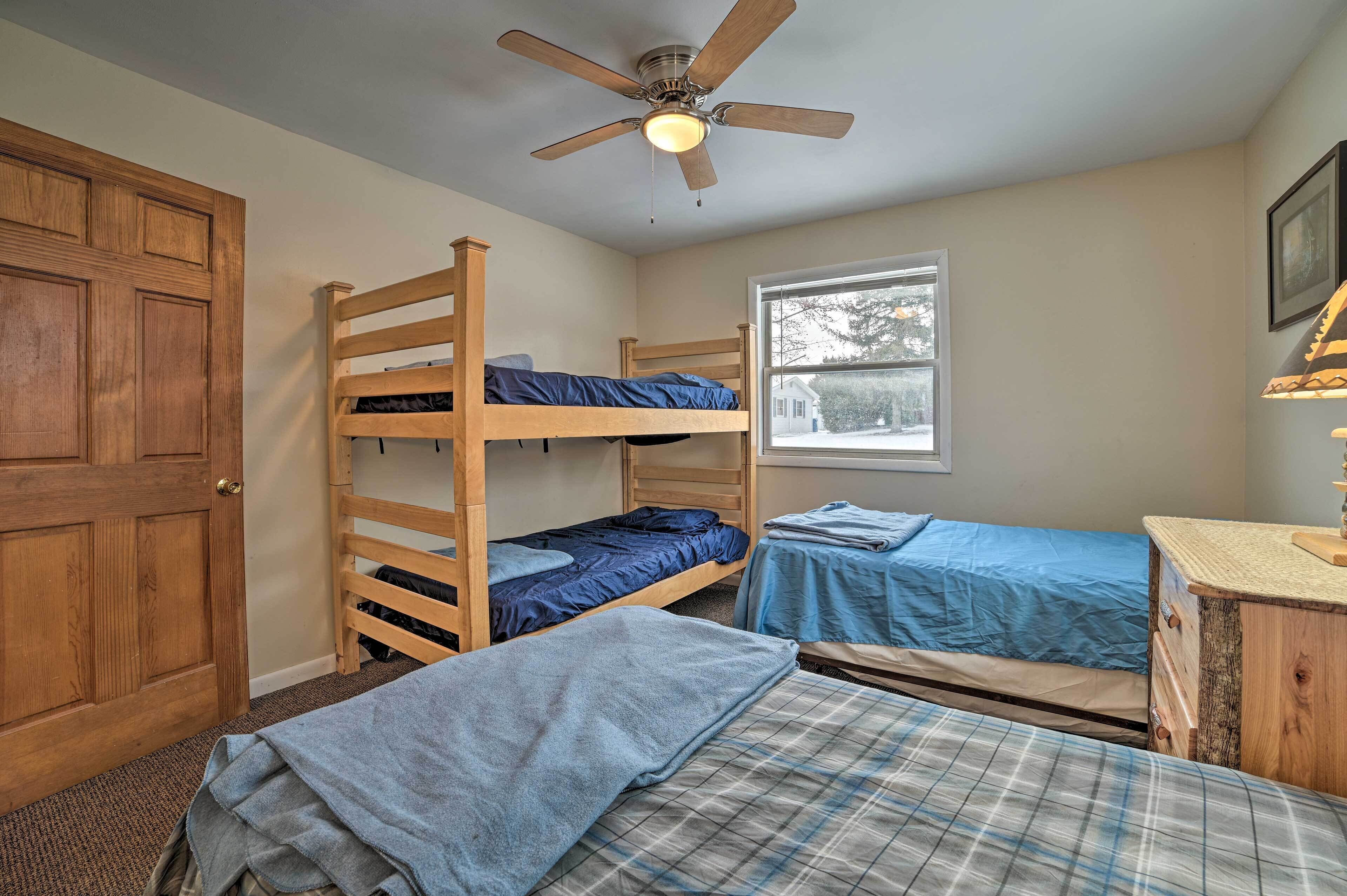 Un dormitorio con literas, un ventilador de techo, una ventana y una puerta de madera.