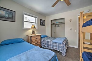 Un dormitorio con dos camas, un tocador, una ventana con lámpara, un armario y una cama nido.