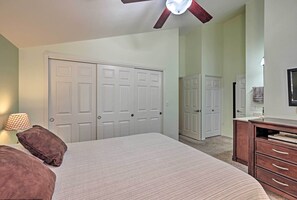 Une chambre à coucher avec un grand lit, un ventilateur de plafond et une commode avec des tiroirs.