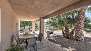 Une terrasse extérieure avec une table et des chaises, un barbecue et des palmiers.