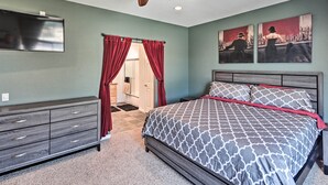 Une chambre à coucher avec un lit, un ventilateur de plafond, une commode et un téléviseur.