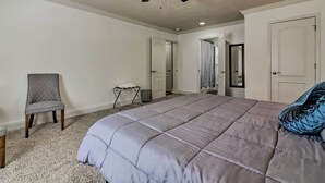 Ein Schlafzimmer mit einem großen Bett, einem Deckenventilator und einem Sessel.