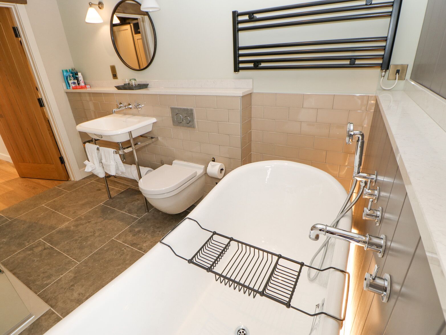 A modern bathroom with a white bathtub, a separate toilet, and a sink.