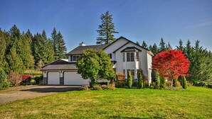 A two-story house with a garage, surrounded by a well-maintained lawn and trees. - Peaceful, Pet-friendly Washougal Paradise! (Washougal)