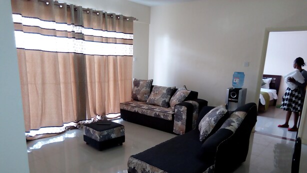 A living room with a sofa set, a coffee table, and a TV. - Apartment Sleeps 6 With Free Parking (Nairobi)