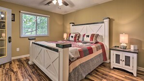 A bedroom with a bed, a nightstand, a ceiling fan, a window, and a door. - 1 Mi to Parkway! Flat-access Pigeon Forge Condo (Pigeon Forge)