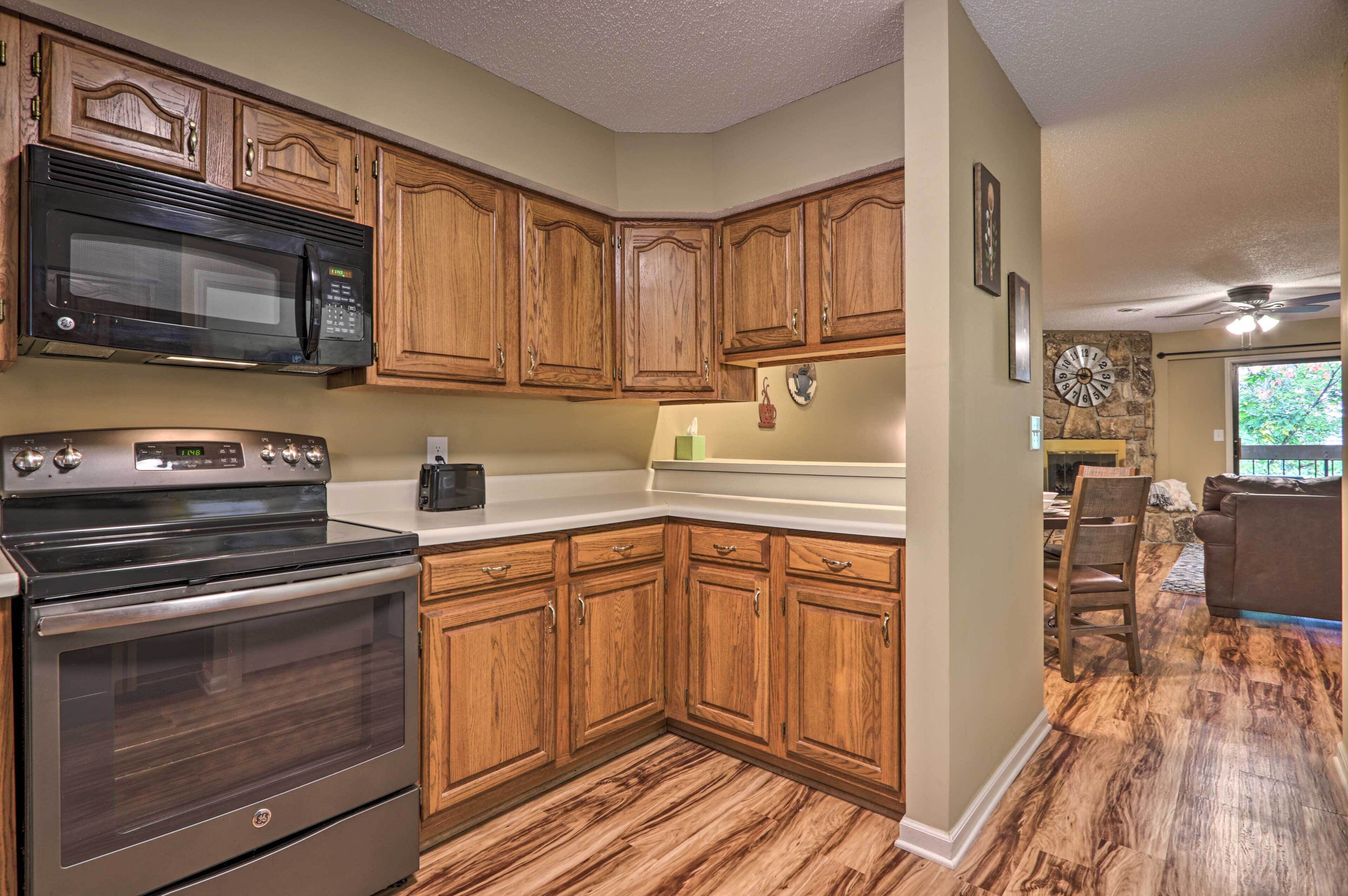 A kitchen with wooden cabinets, a stainless steel microwave, and an oven.