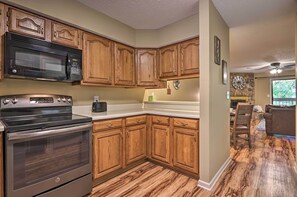 A kitchen with wooden cabinets, a stainless steel microwave, and an oven.