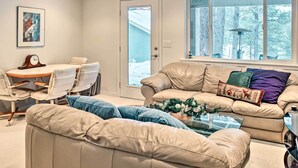 Ein Wohnzimmer mit beiger Couch, einem Couchtisch und einem Essbereich mit Tisch und Stühlen.