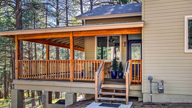 Ein zweistöckiges Haus mit einer Holzterrasse und einer Veranda.