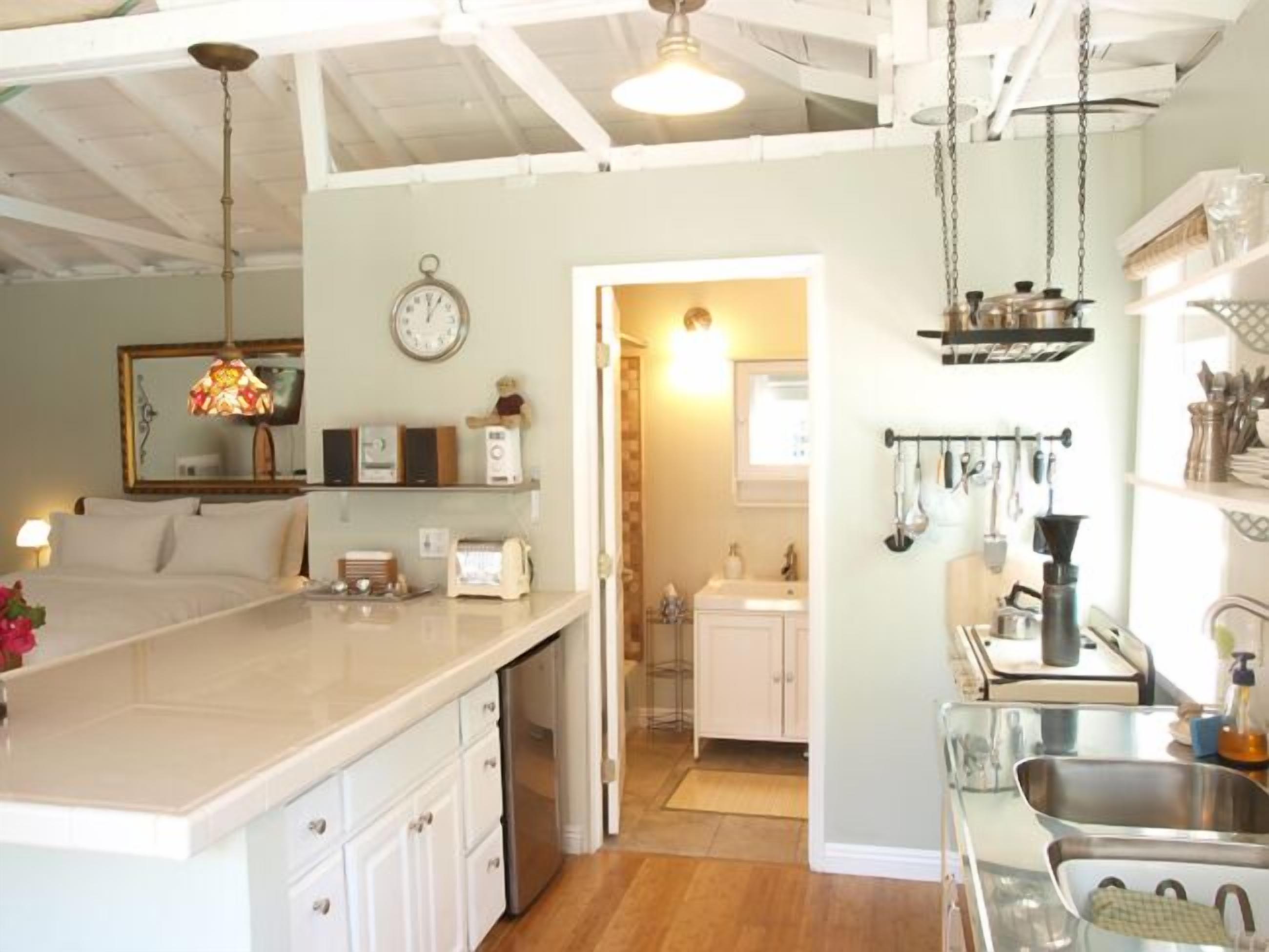 A spacious kitchen with a large island, a dining area with a chandelier, and a visible clock on the wall.