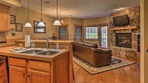 A spacious kitchen with a central island, a stone fireplace, and a cozy seating area with a leather couch.