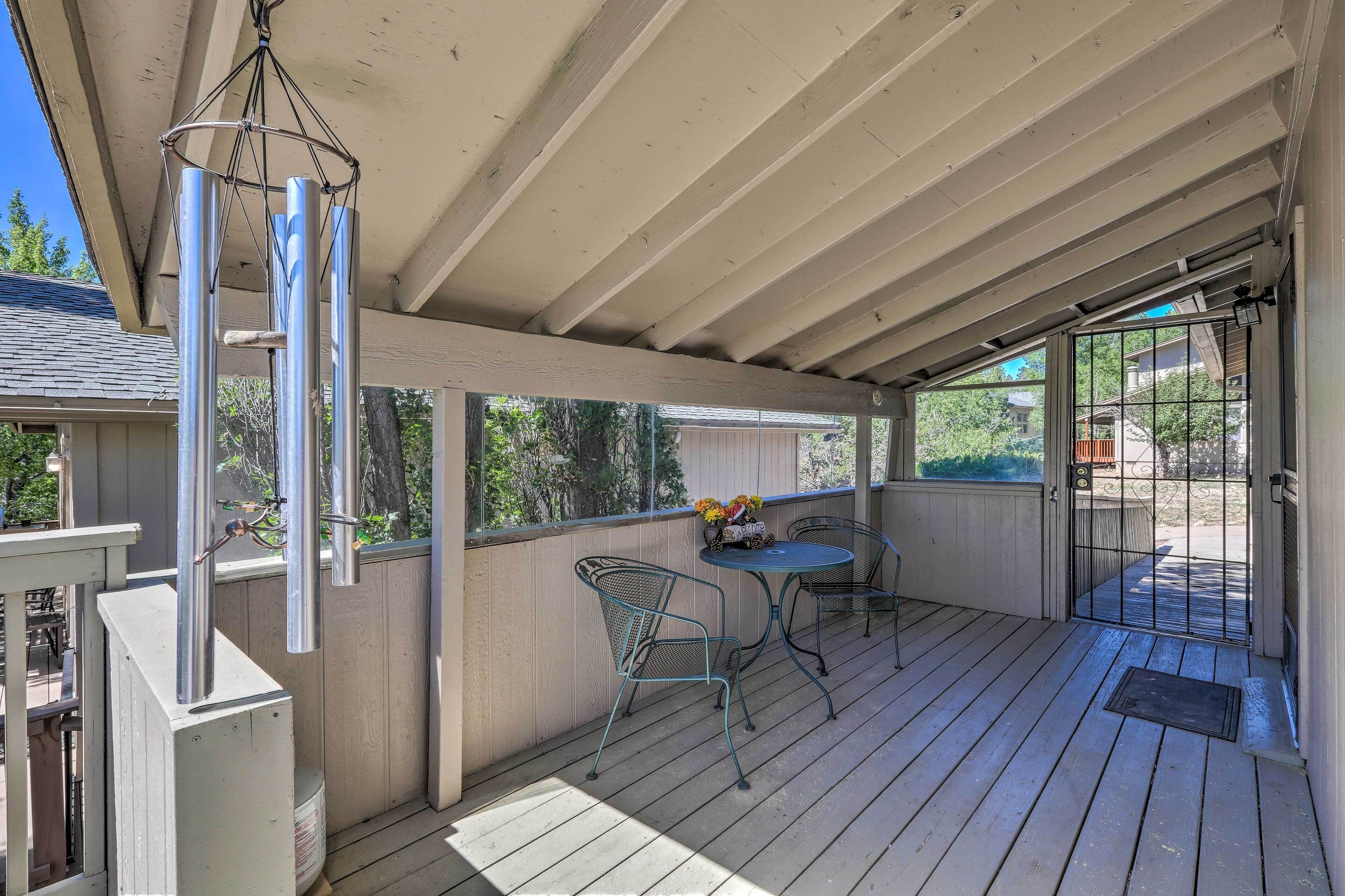 A covered patio with a table and chairs, a hanging wind chime, and a view of the backyard.