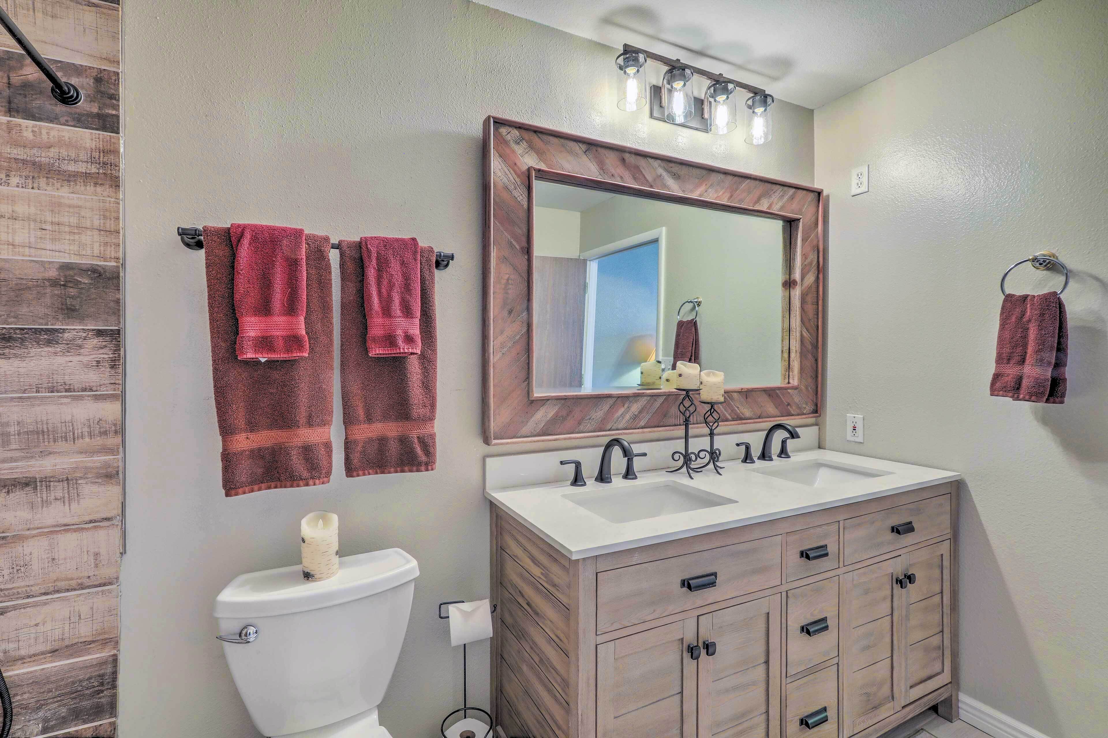 A bathroom with a wooden vanity, a white sink, and a large mirror.