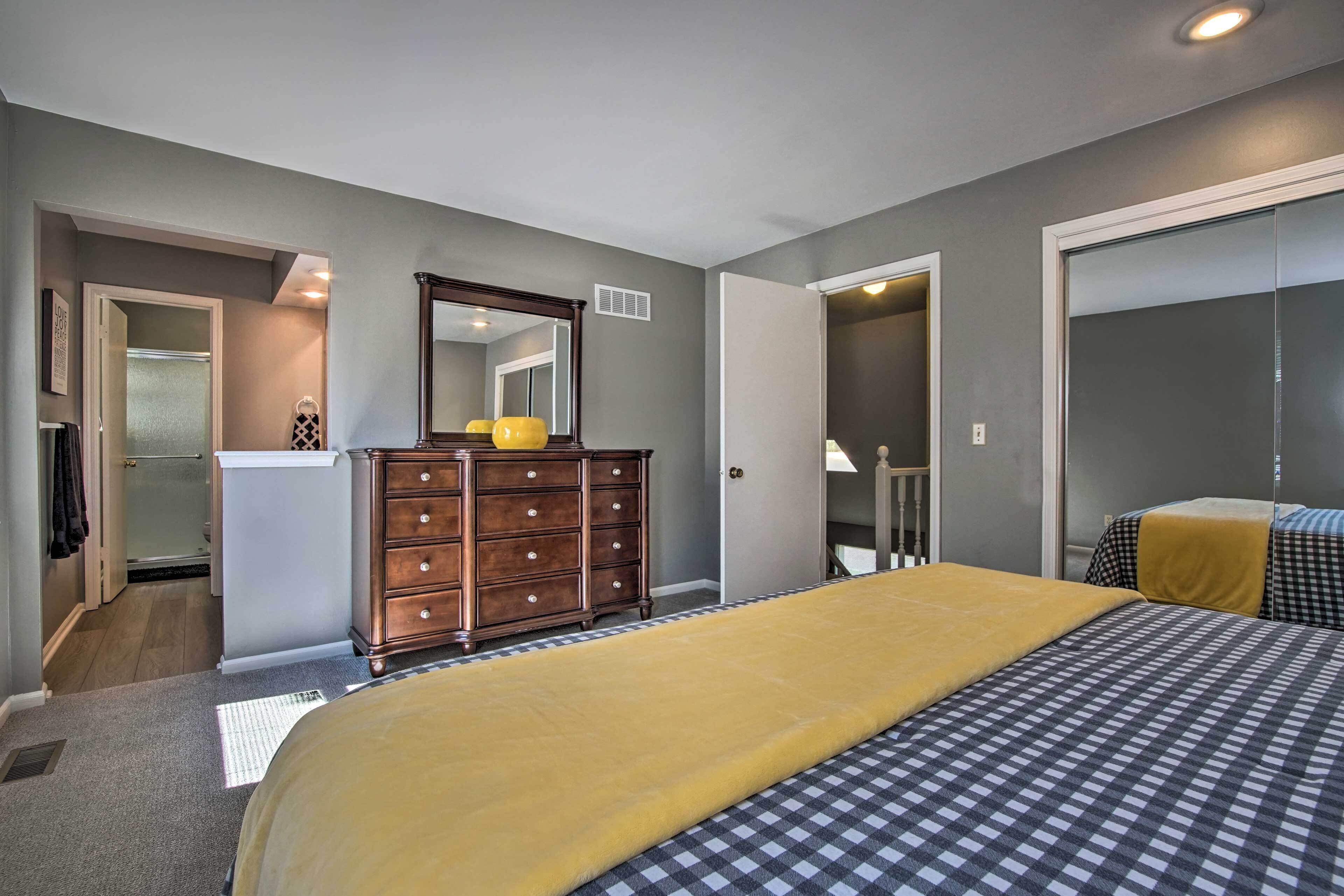Een slaapkamer met een bed, een dressoir en een spiegel.