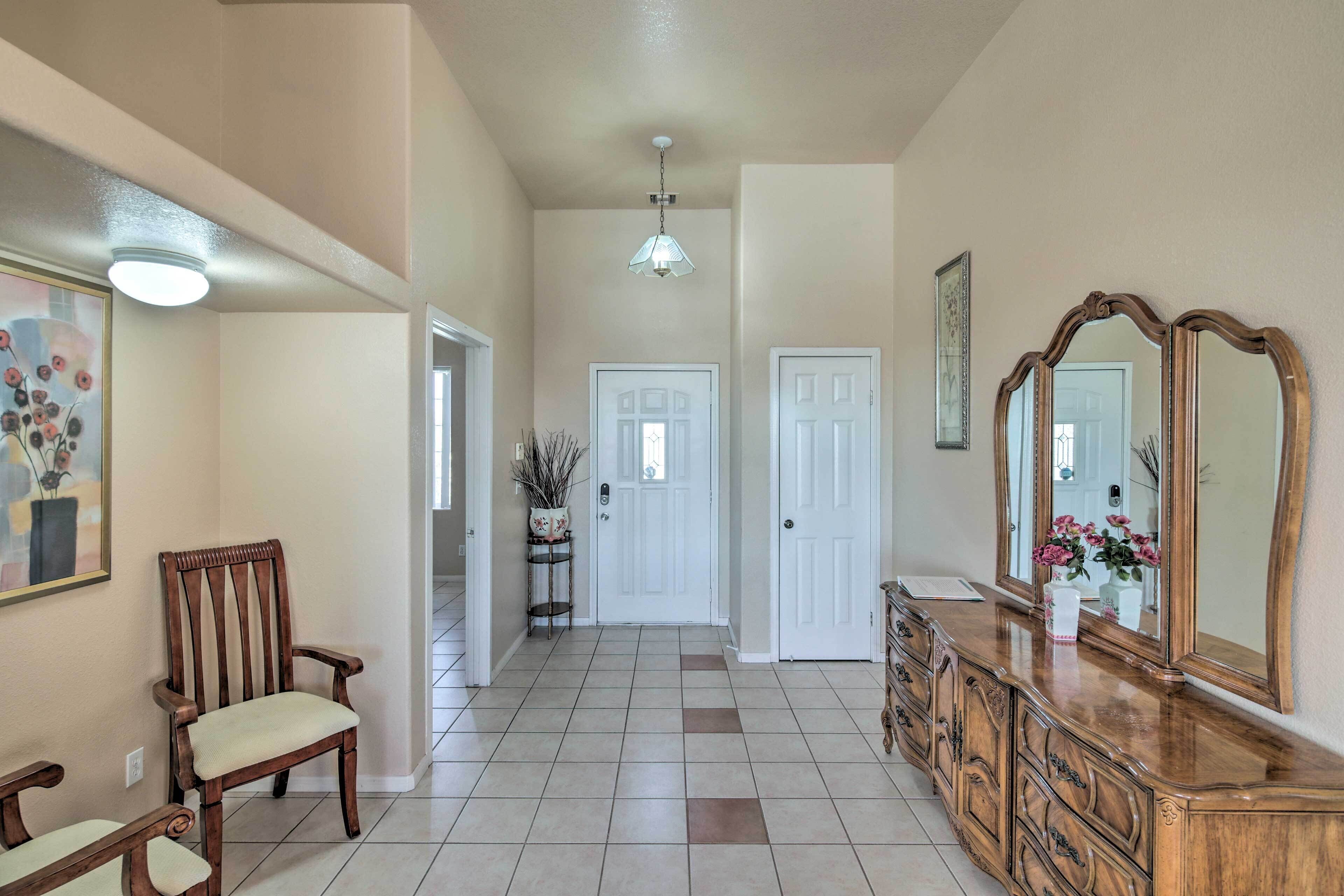 A hallway with a wooden chair, a dresser with a mirror, and a door.