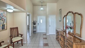 A hallway with a wooden chair, a dresser with a mirror, and a door.