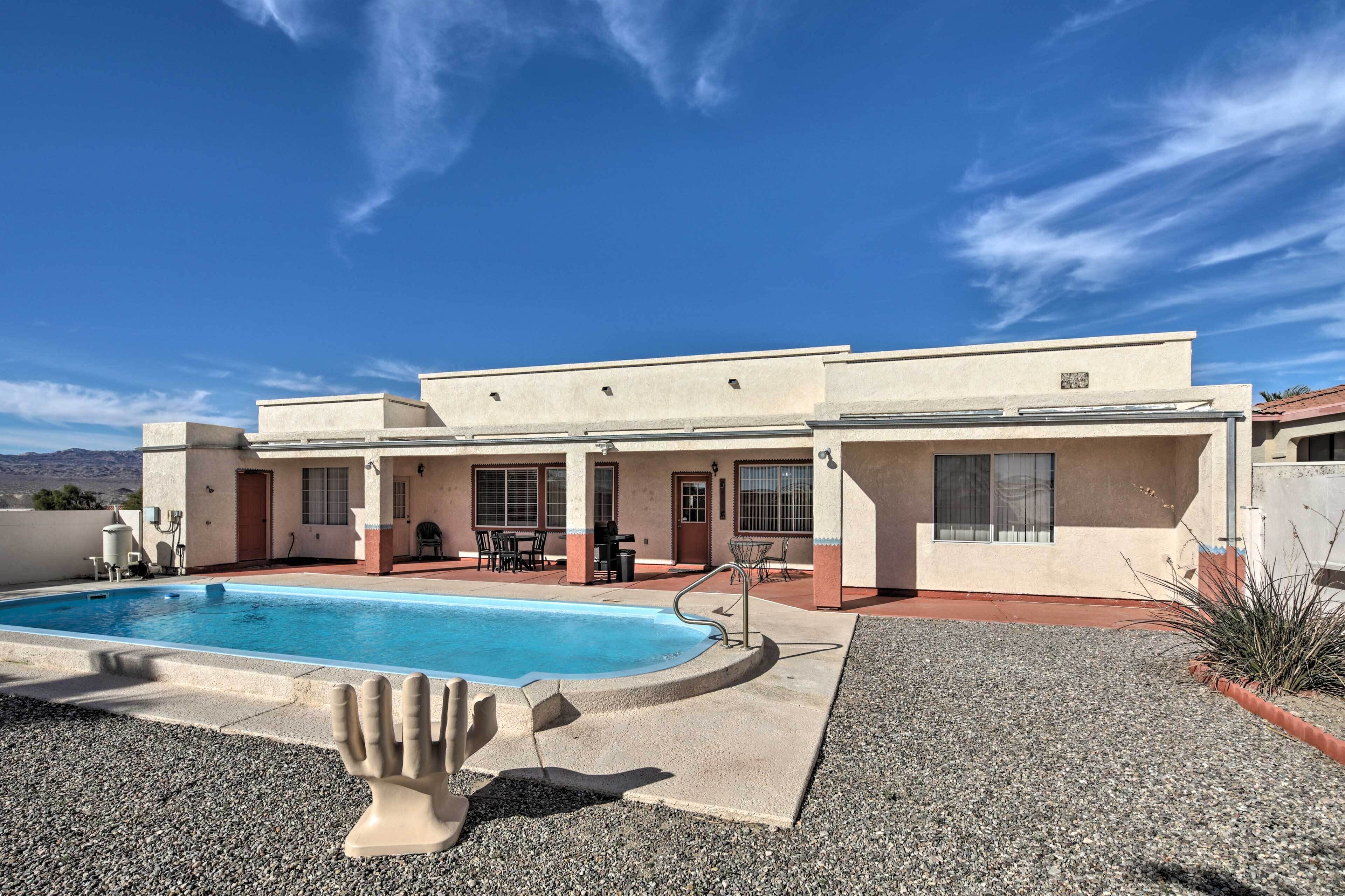 A two-story building with a swimming pool, outdoor seating, and a clear blue sky.