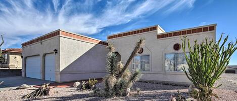 A modern building with a flat roof, a garage, and a desert garden with cacti.
