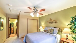 A bedroom with a bed, a ceiling fan, a nightstand with a lamp, and a wall-mounted plant. - Relax Fireside! Peaceful Forest Haven in Prescott (Prescott)