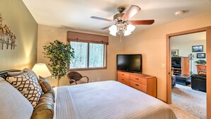 A bedroom with a bed, a ceiling fan, a TV, a dresser, and a window with blinds. - Relax Fireside! Peaceful Forest Haven in Prescott (Prescott)
