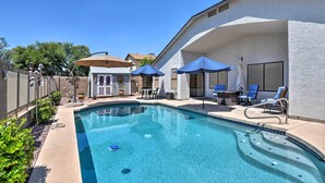 A swimming pool with a sunken hot tub, surrounded by lounge chairs and umbrellas, with a covered patio area and a view of the neighborhood. - Walk to NFL Games: Glendale Home Near Golf (Glendale)