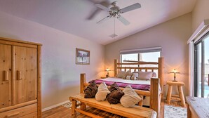 A bedroom with a wooden bed, a wooden bench, a wardrobe, and a ceiling fan. - Walk to NFL Games: Glendale Home Near Golf (Glendale)