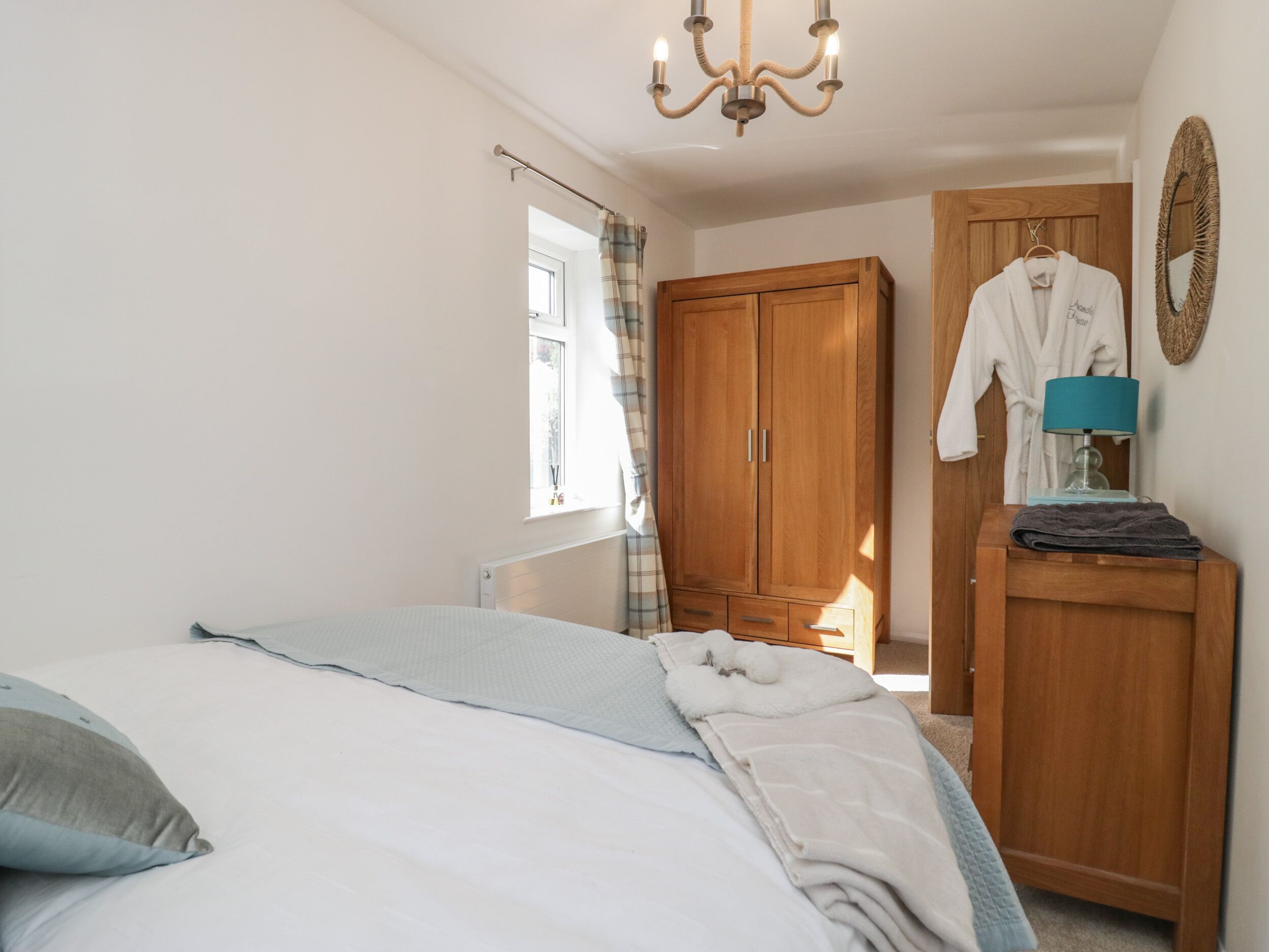 Une chambre à coucher avec un lit, une armoire en bois et une fenêtre avec des rideaux.