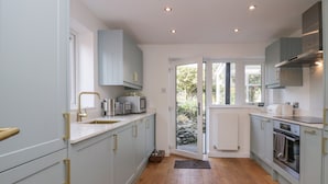 Une cuisine moderne avec des meubles de couleur gris clair, une hotte de cuisine en acier inoxydable et un plancher en bois.