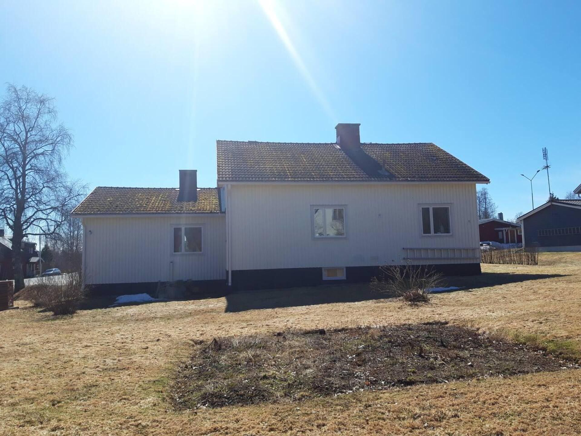 A single-story house with a gabled roof, a chimney, and a small front yard with a patch of snow.