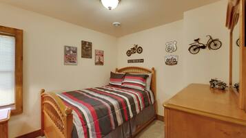 A bedroom with a bed, wooden headboard, and a dresser. There are wall decorations including a motorcycle and Route 66 signs.