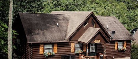 A log cabin with a front porch, a mailbox, and a sign indicating it is a guesthouse.