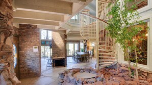 Un interior amplio con chimenea de piedra, un comedor y una escalera que lleva a un nivel superior.
