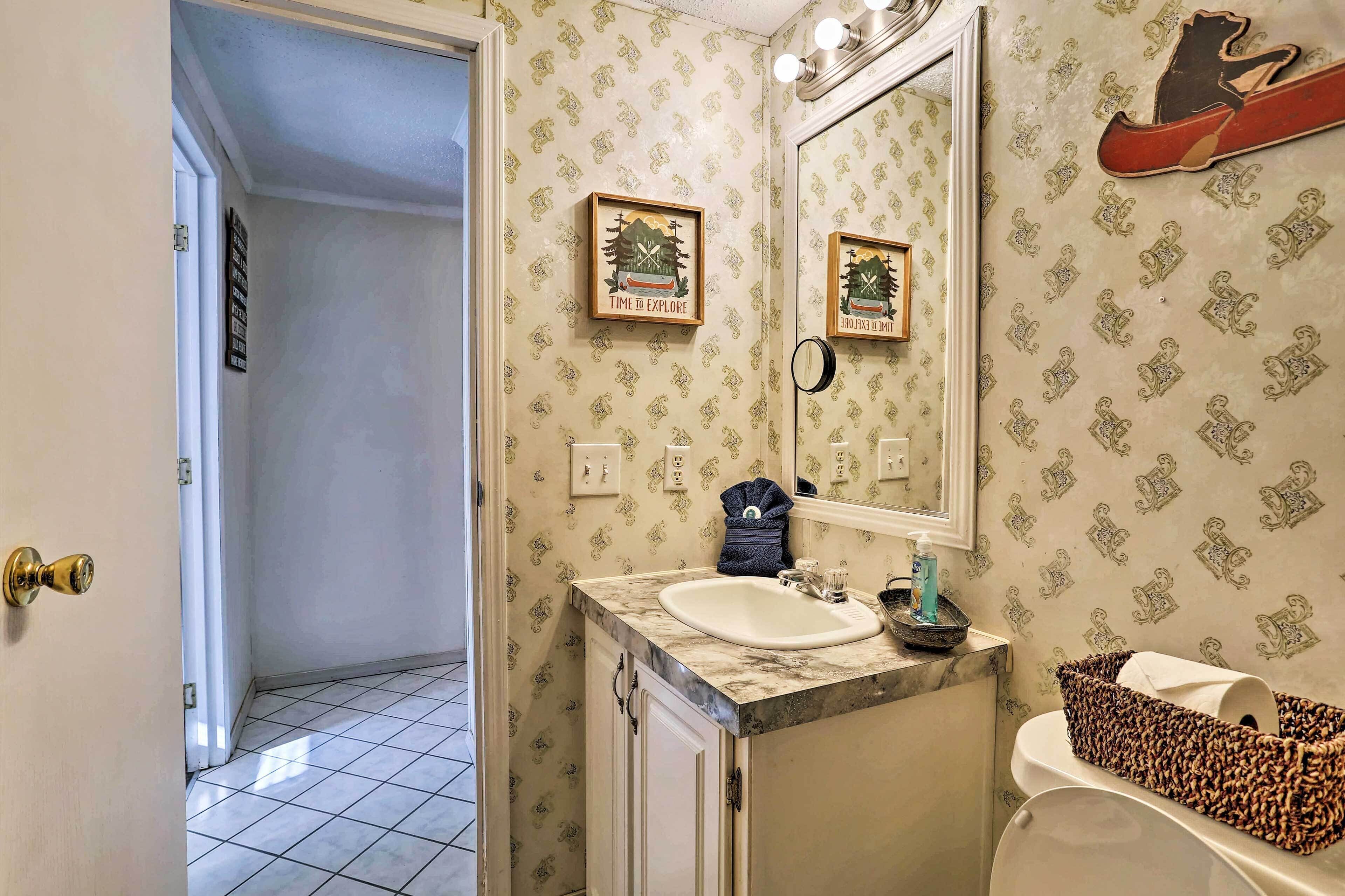 A bathroom with patterned wallpaper, a sink, a mirror, and a toilet.