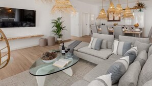 A modern living room with a large sectional sofa, a glass coffee table, and multiple hanging wicker lamps. - KARAT Villa Uchova - Cho Pancho (El Frontón)