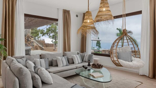 A modern living room with a sectional sofa, a glass coffee table, and a hanging chair. - KARAT Villa Uchova - Cho Pancho (El Frontón)