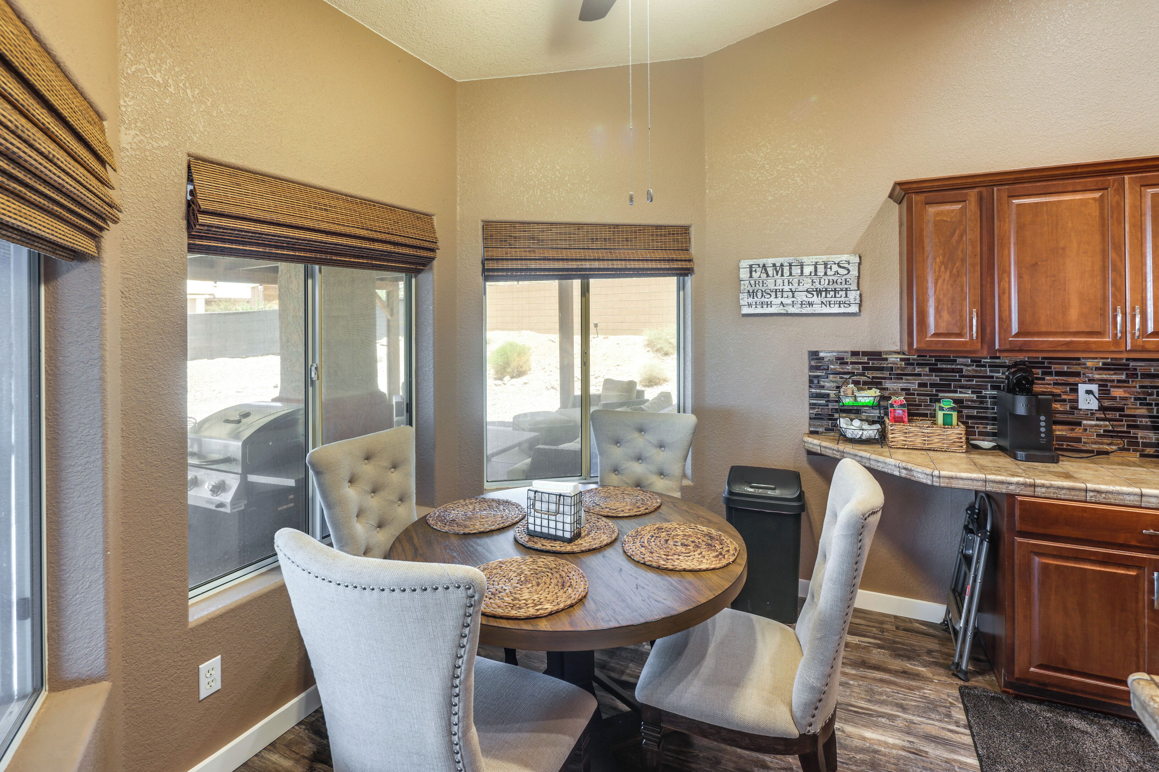 A dining area with a round table, six chairs, and a kitchen counter with cabinets and appliances.