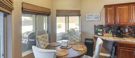 A dining area with a round table, six chairs, and a kitchen counter with cabinets and appliances.
