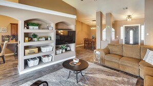 A spacious living room with a beige sofa, a coffee table, and a built-in shelving unit with decorative items.