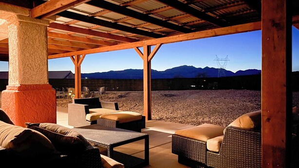 An outdoor seating area with wicker furniture and a view of mountains and a power line tower.