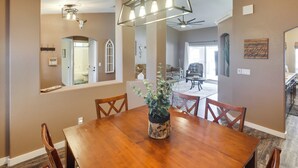 A dining area with a wooden table and chairs, a hanging light fixture, and a plant centerpiece.