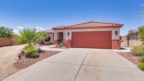 A single-story house with a red garage door, a concrete driveway, and a small garden with desert plants.