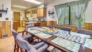 A dining area with a long wooden table, checkered tablecloths, and patterned chairs. - 10 Mi to Show Low: Pinetop-lakeside Family Cabin! (Lakeside)