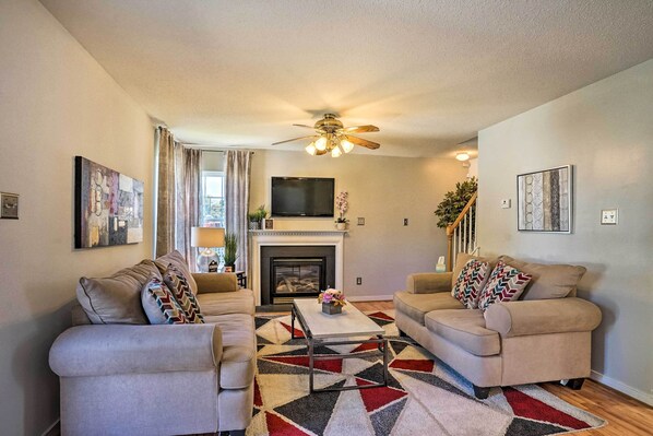 A living room with two beige sofas, a coffee table, a fireplace, and a ceiling fan.