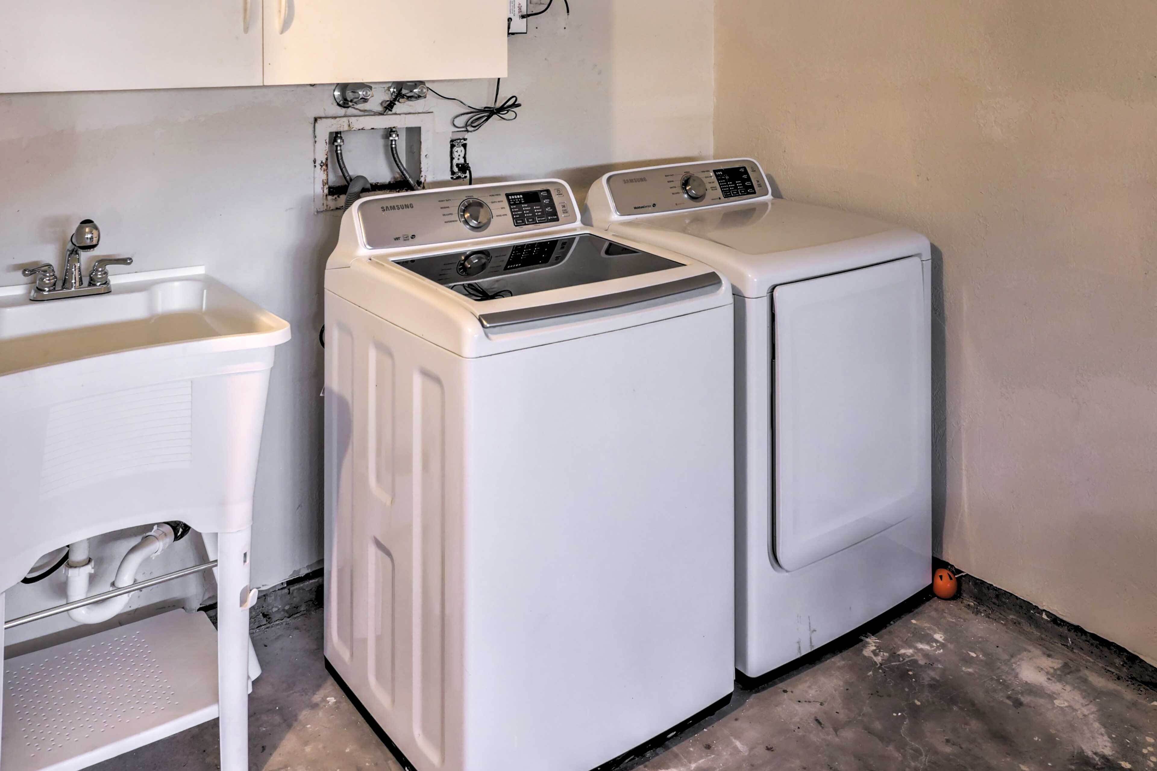 Un espace buanderie comprenant deux machines à laver Samsung blanches, un évier et un marchepied.