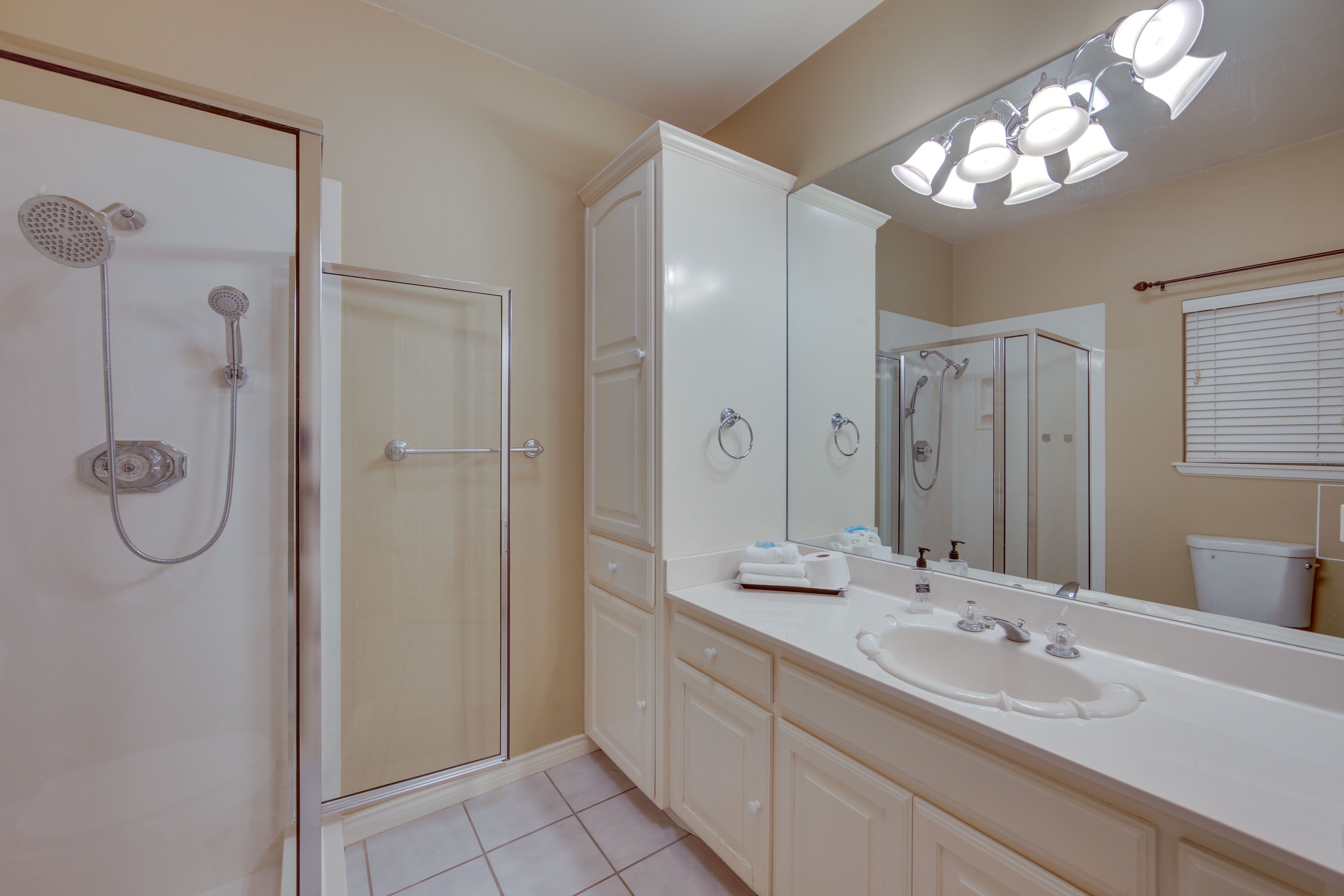 Une salle de bain avec une douche à l’italienne, un grand miroir et un lavabo blanc.
