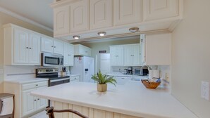 Une cuisine moderne avec des meubles blancs, un îlot central et des appareils électroménagers intégrés.